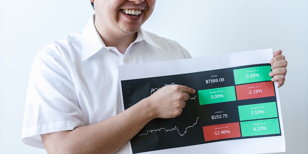 A man holds a sheet with a picture of a graph and prices