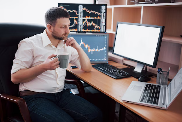 A man sits in an office at a table, working on a computer