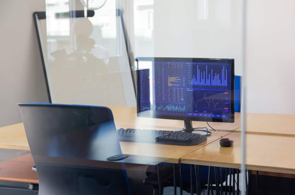 A computer with financial analysis graphs onscreen, seen through an office partition